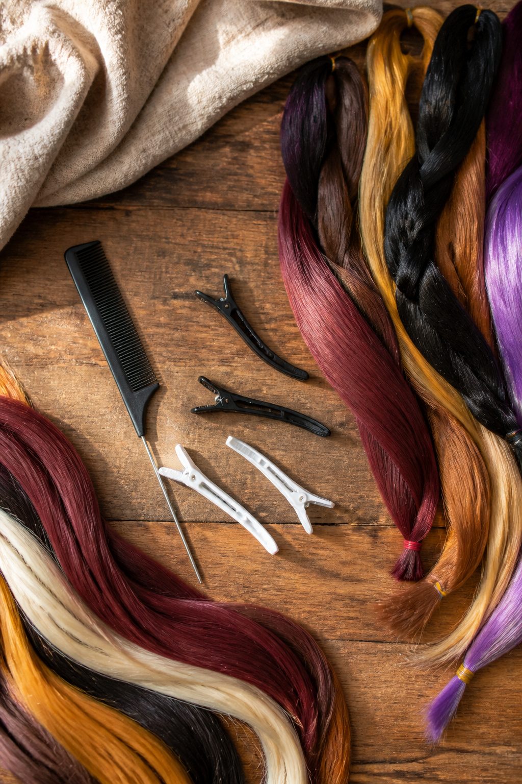 A fine-tooth comb, sectioning clips, and hair extensions on a flat surface.