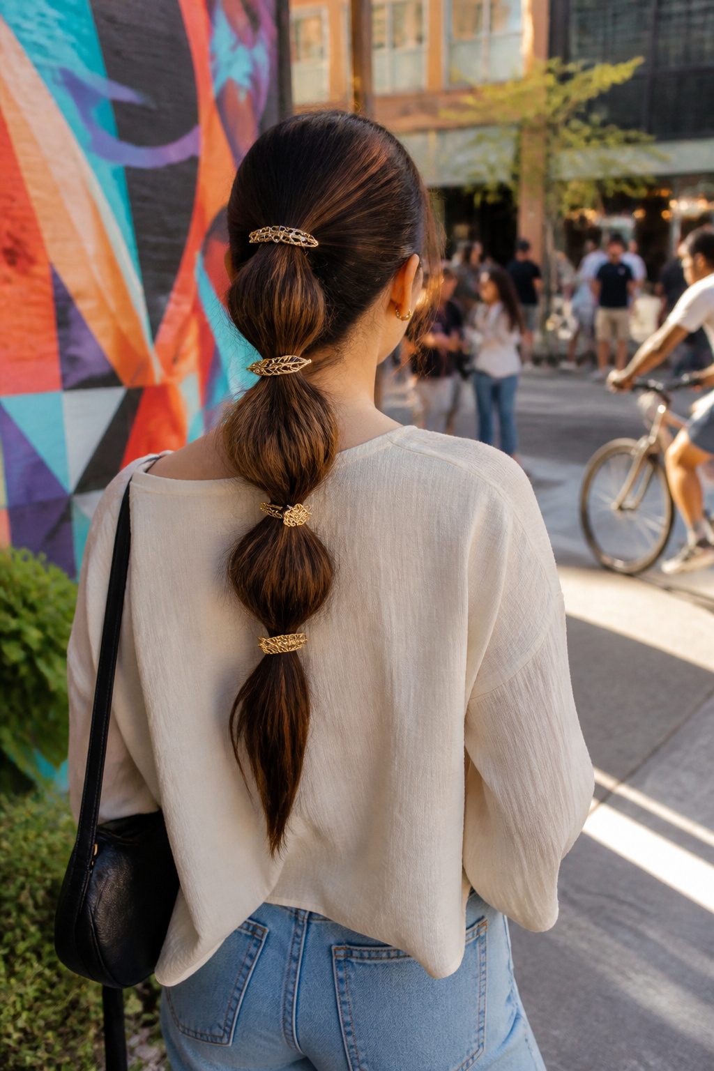 Bubble ponytail with barrettes pinned against elastics in a vibrant urban setting.