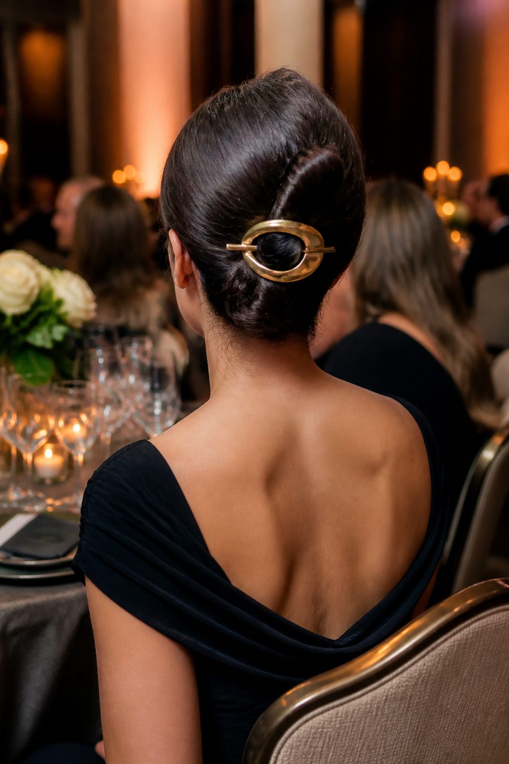 French Twist hairstyle secured with a large barrette at a stylish event.